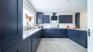 A modern kitchen with dark cabinetry, white countertops, and a tiled floor.
