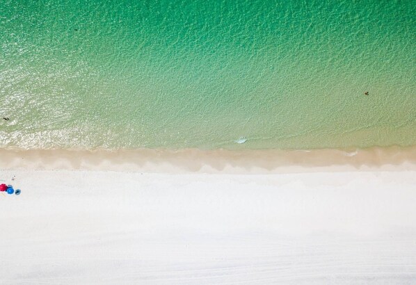 A beach with clear turquoise water, a sandy shore, and a few scattered objects.