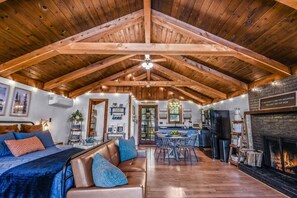 A spacious loft with a high ceiling, a fireplace, a dining area, and a cozy seating area. - Cliff Haven 1 Bedroom Cabin by RedAwning (Townsend)