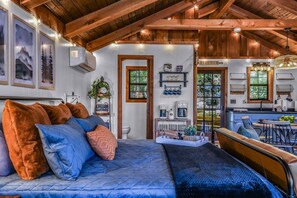A cozy room with a bed, a wooden ceiling, a kitchen area, and a dining table. - Cliff Haven 1 Bedroom Cabin by RedAwning (Townsend)