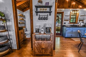 A rustic interior with a wooden floor, a coffee station, and a kitchenette. - Cliff Haven 1 Bedroom Cabin by RedAwning (Townsend)