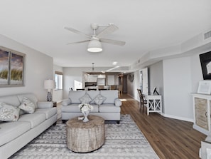 Ein geräumiges Wohnzimmer mit Deckenventilator, zwei Sofas, einem Couchtisch und einem Essbereich im Hintergrund.