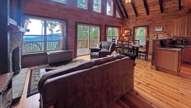 A spacious cabin with a fireplace, a large sofa, a dining area, and a kitchen. - High Mountain Cabin Long Range Mountain Views at 4,000 Ft above Sea Level (Bryson City)