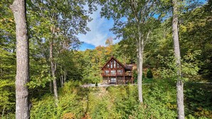 A cabin surrounded by dense forest with a stone foundation and wooden exterior. - High Mountain Cabin Long Range Mountain Views at 4,000 Ft above Sea Level (Bryson City)