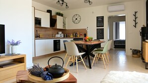A modern kitchen with a dining area, a TV, and a clock on the wall. - Villa Lavanda Muntrilj with pool (Muntrilj)