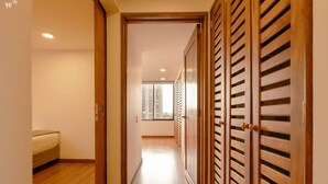 A hallway with wooden sliding doors, a bed, and a view of high-rise buildings.