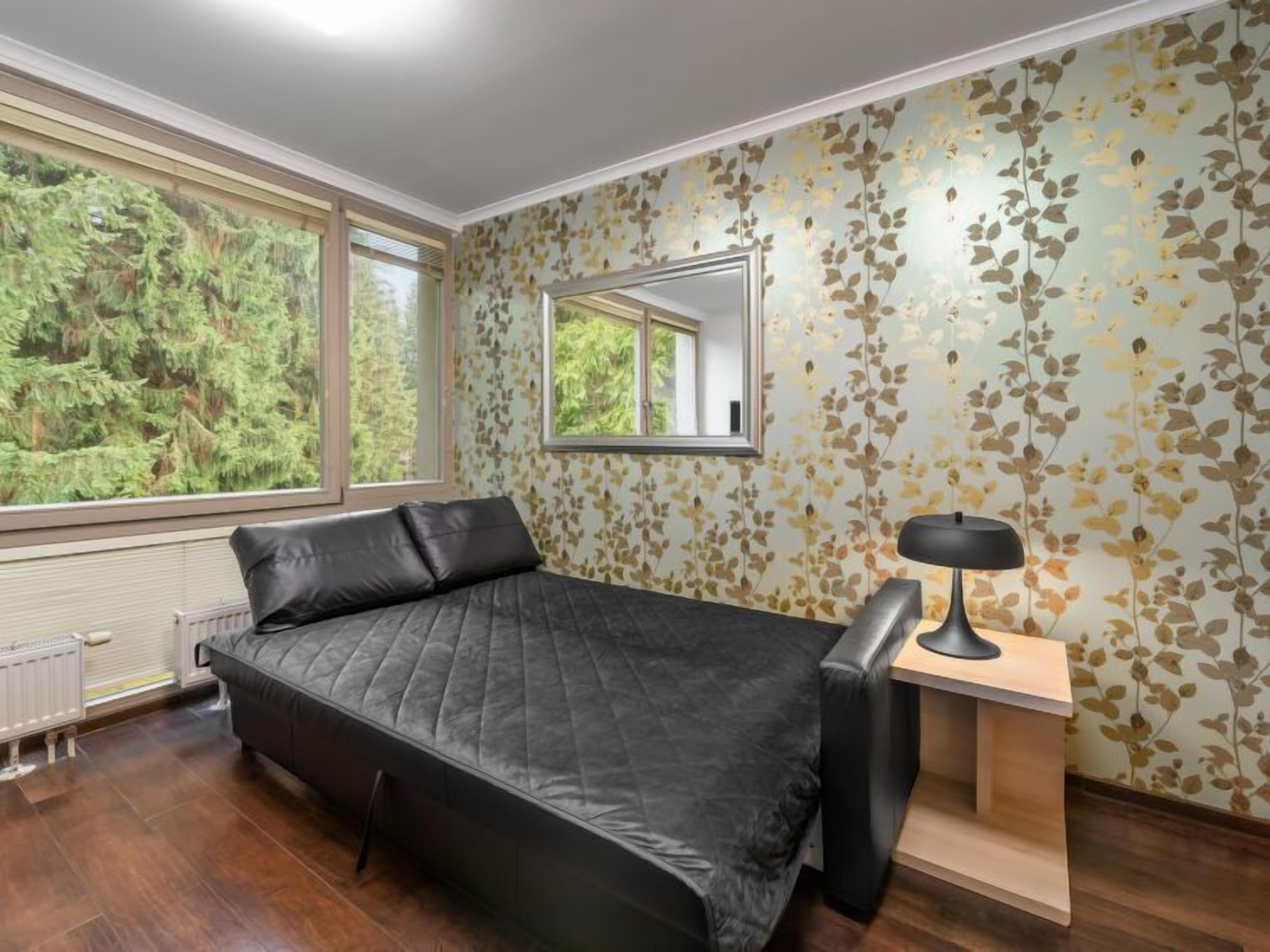 Ein Schlafzimmer mit Bett, Schreibtisch und Fenster mit Blick auf Bäume.