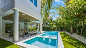 A modern house with a swimming pool, outdoor seating, and lush greenery.