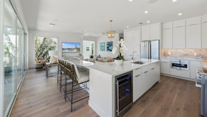 A modern kitchen with a large island, stainless steel appliances, and a view of the outdoors.