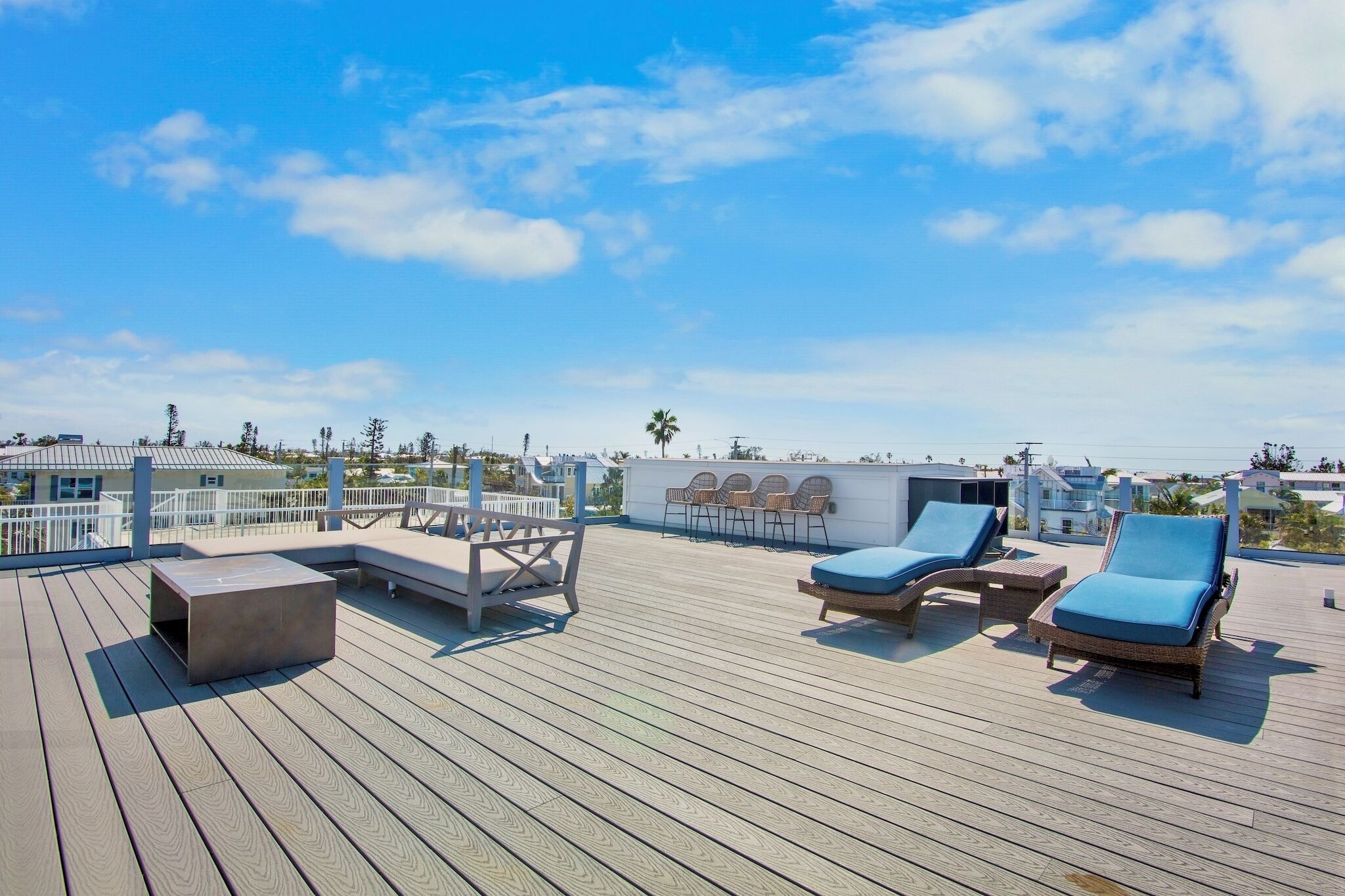 Une terrasse en bois avec des chaises longues et une table, offrant une vue sur le paysage urbain.