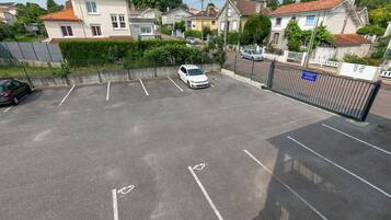 A parking lot with marked spaces, a white car parked, and a gated entrance.