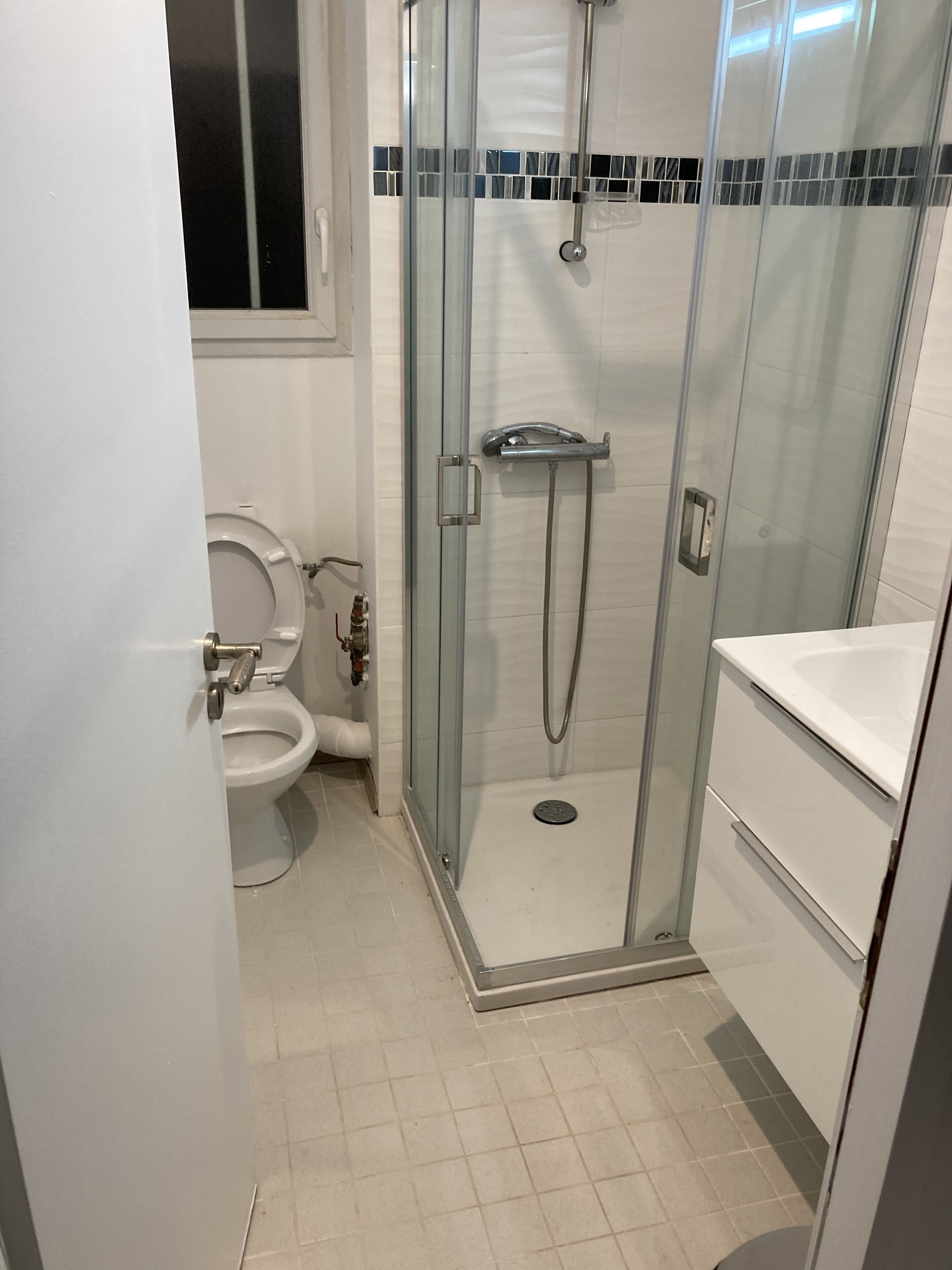 A bathroom with a glass-enclosed shower, a toilet, and a sink.