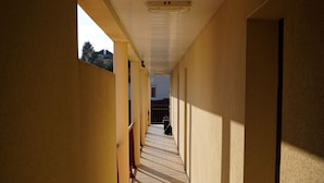 A corridor with tiled floors and a sloped ceiling, leading to a door at the end. - Apparts Confort 87 (Limoges)