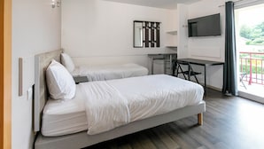 A modern hotel room with a large bed, a desk, a TV, and a balcony with a red railing. - Apparts Confort 87 (Limoges)
