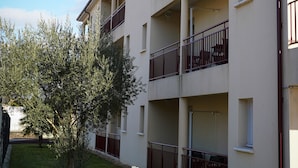 A multi-story building with balconies and a grassy area in front. - Apparts Confort 87 (Limoges)