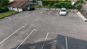 A parking lot with marked spaces, a white car, and a black car parked.