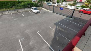 Een parkeerplaats met aangegeven parkeerplaatsen, een hek en een rode auto erin.
