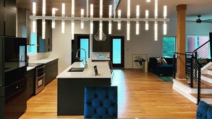 A modern kitchen with a central island, pendant lighting, and a staircase leading to a loft area. - New Modern 4BR Smart Home Downtown Atlanta GWCC (Atlanta)