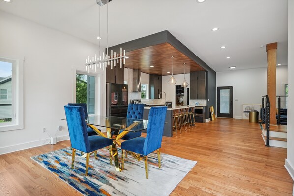 Une cuisine moderne avec des meubles de couleur sombre, un îlot central et des luminaires suspendus.