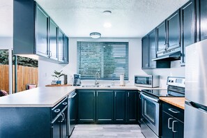 Een moderne keuken met donkere kastjes, een roestvrijstalen koelkast, een magnetron en een fornuis.