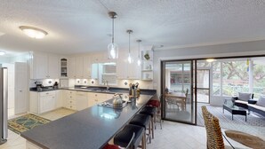 Una cocina moderna con una isla grande, armarios blancos e iluminación colgante.