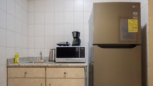 Een keuken met een magnetron, koffiezetapparaat en een koelkast.