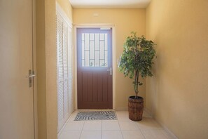 A hallway with a door, a potted plant, and a zebra-patterned mat.