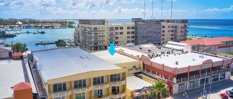Un hotel frente al mar con varios pisos, balcones y vistas al puerto deportivo y al océano.