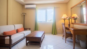 A hotel room with a sofa, a wooden table, a chair, a lamp, and a mirror. - NEW ! Bay Harbor studio 202 (Oranjestad)