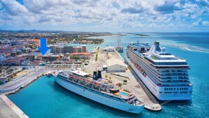 A cruise ship docked at a port with a cityscape in the background. - NEW ! Bay Harbor studio 202 (Oranjestad)