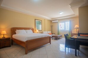 A hotel room with a wooden bed, a small table, a chair, and a desk. - NEW ! Bay Harbor studio 202 (Oranjestad)