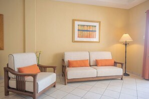 A room with a sofa, a chair, a floor lamp, and a framed picture on the wall.