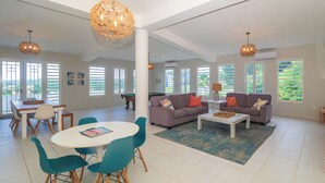 A spacious living area with a pool table, two sofas, a coffee table, and a dining table with chairs. - Hideaway with Wraparound Balcony: Beautiful Views, Great Vibes, Family Friendly (Luquillo)