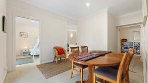 Un comedor acogedor con una mesa y sillas de madera, un tapete tejido y una estantería en el fondo.