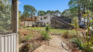 Una propiedad residencial con terraza de madera, una escalera que lleva a un área exterior cubierta y un jardín cercado.