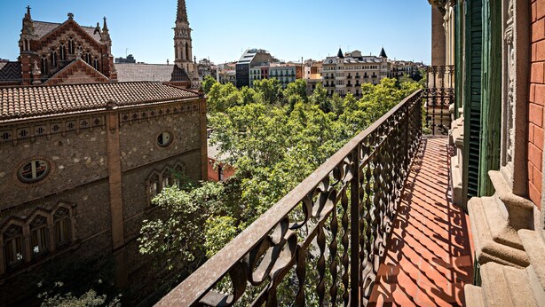 Une vue depuis un balcon donnant sur un paysage urbain, avec des bâtiments historiques et une église.