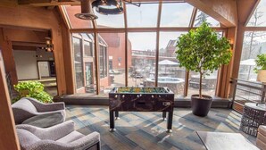 A cozy indoor space with a foosball table, comfortable seating, and large windows offering a view of the cityscape.