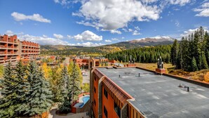 A hotel with a rooftop pool, surrounded by autumn trees and mountains in the background.