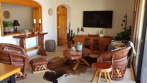 Una sala de estar con una mesa de centro de madera, sofás de cuero, un televisor y un ventilador de techo.