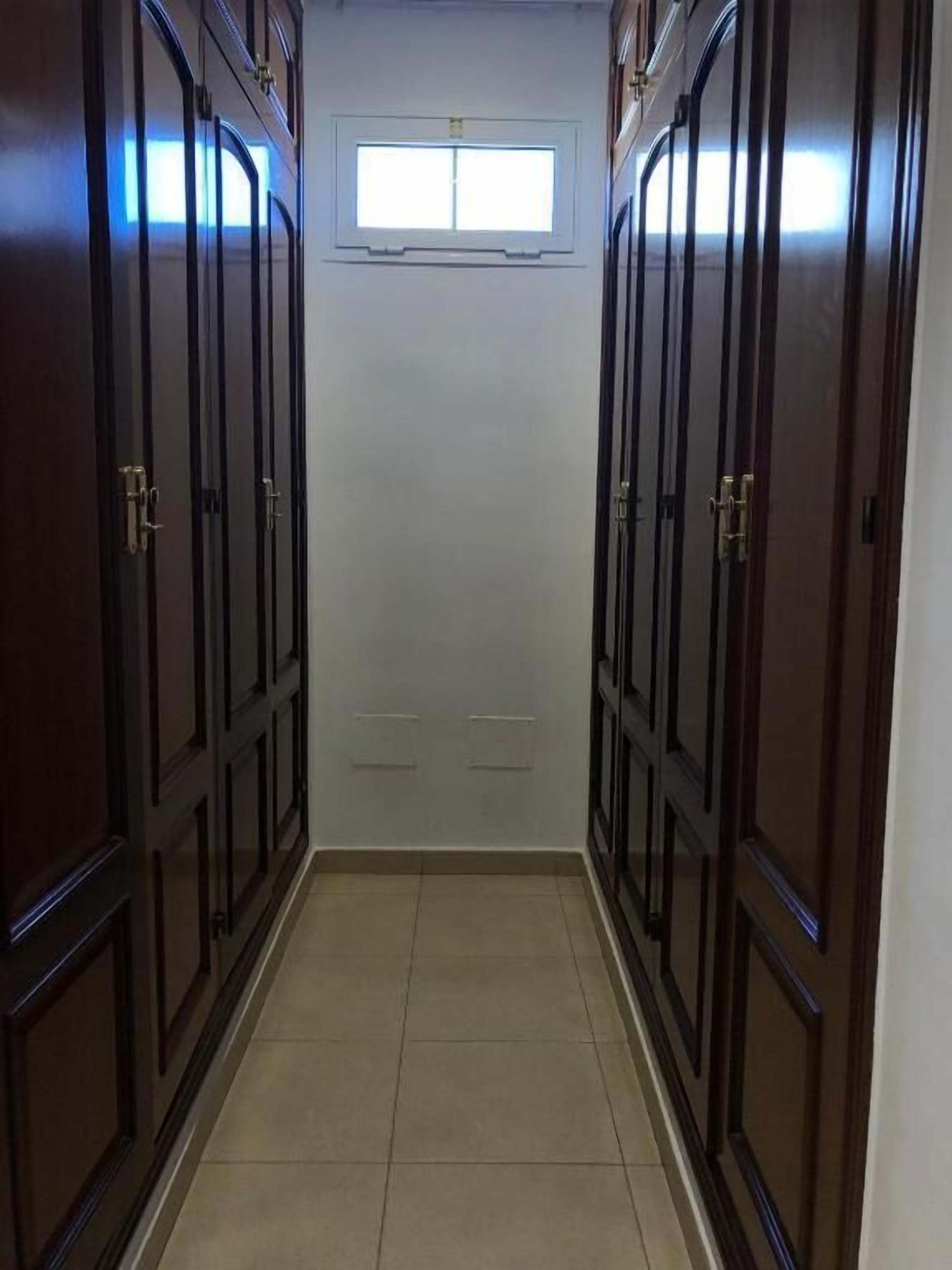 Un pasillo con puertas de madera oscura y una pequeña ventana al final.