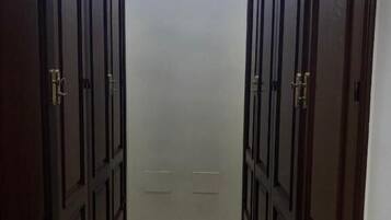 Un pasillo con puertas de madera oscura y una pequeña ventana al final.