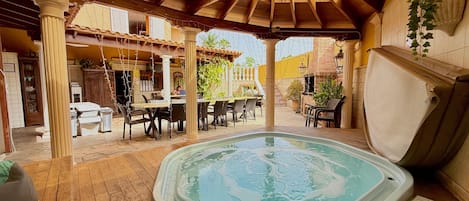 Un jacuzzi en un espacio exterior cubierto, con suelo de madera y mesas.