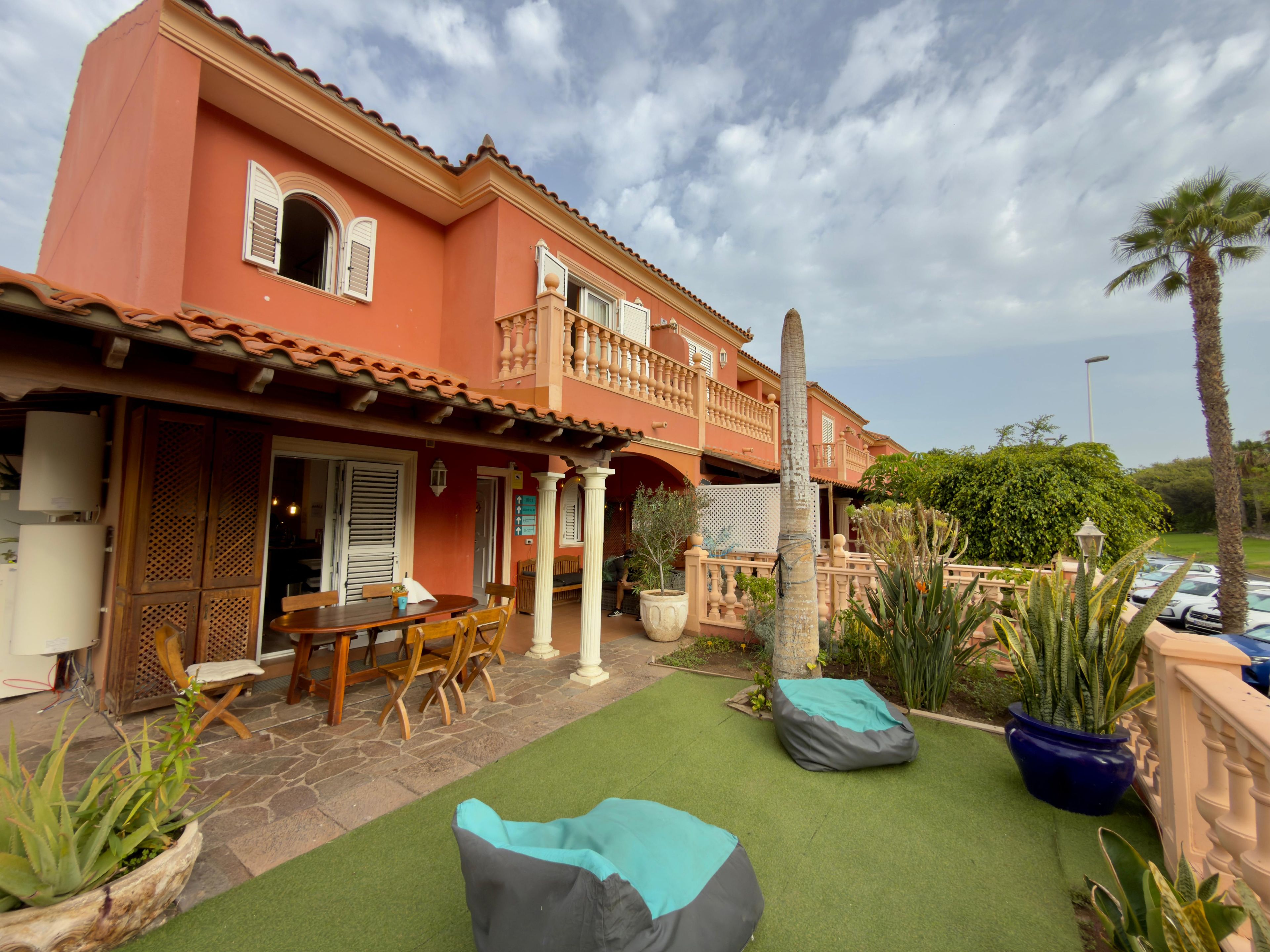 A two-story building with a balcony, outdoor seating, and a cactus.