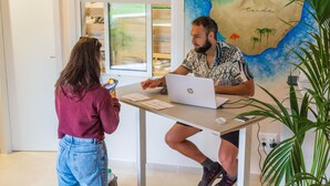 A man and a woman in a room with a large map on the wall, a laptop on a table, and a plant. - Duque Nest Hostel (Adeje)
