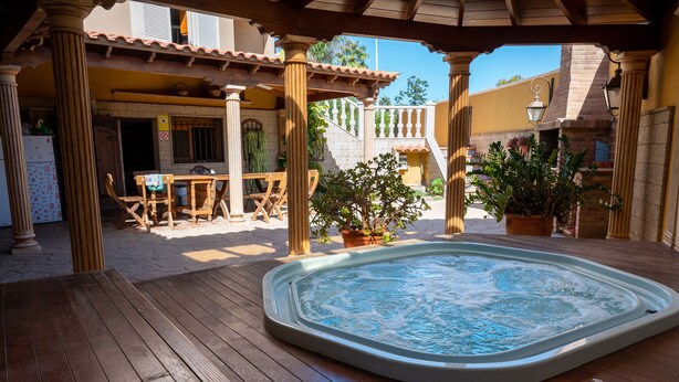 A wooden deck with a hot tub, outdoor furniture, and potted plants. - Duque Nest Hostel (Adeje)