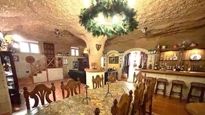 An interior with a stone ceiling, a central table with chairs, a bar area, and a staircase. - Duque Nest Hostel (Adeje)