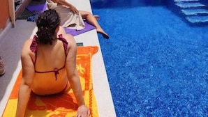 A swimming pool area with people sunbathing and relaxing. - Duque Nest Hostel (Adeje)