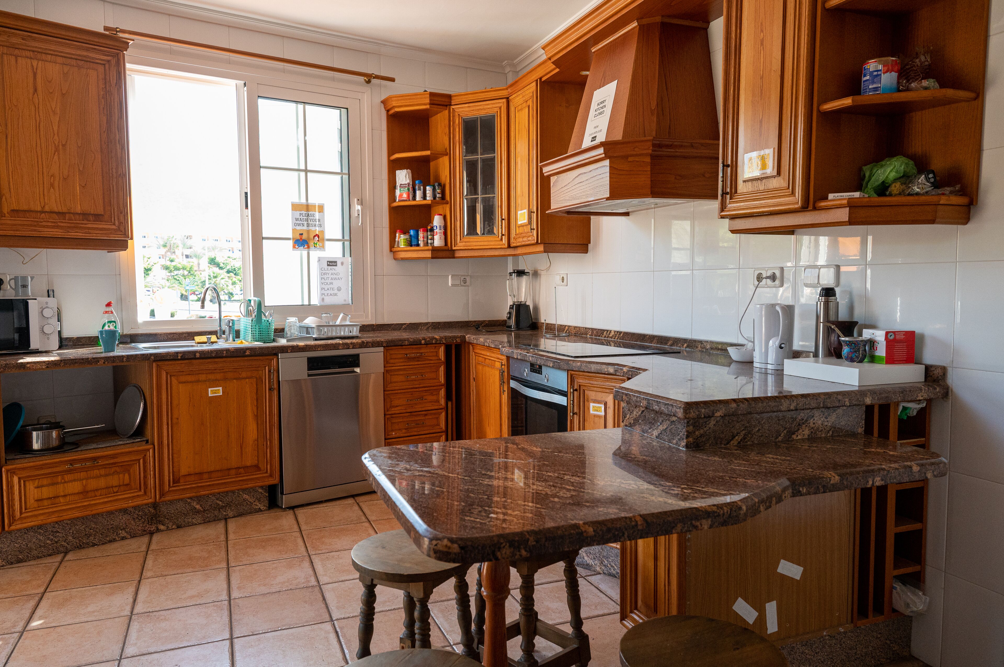 A kitchen with wooden cabinets, a granite countertop, and a built-in dishwasher.