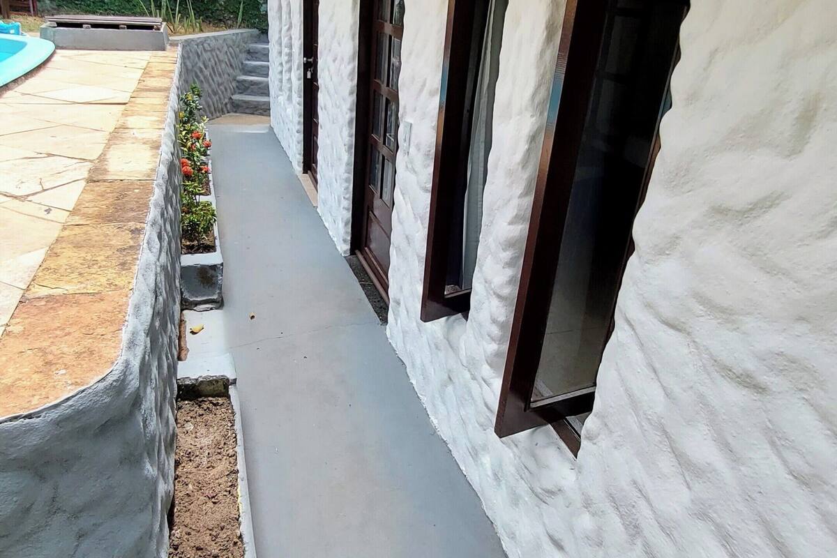A building with a white exterior, a concrete pathway, and a small garden area.