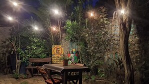 An outdoor seating area with a table and chairs, surrounded by greenery and a stone wall. - Pousada Toa Toa Em Pipa (Tibau do Sul)